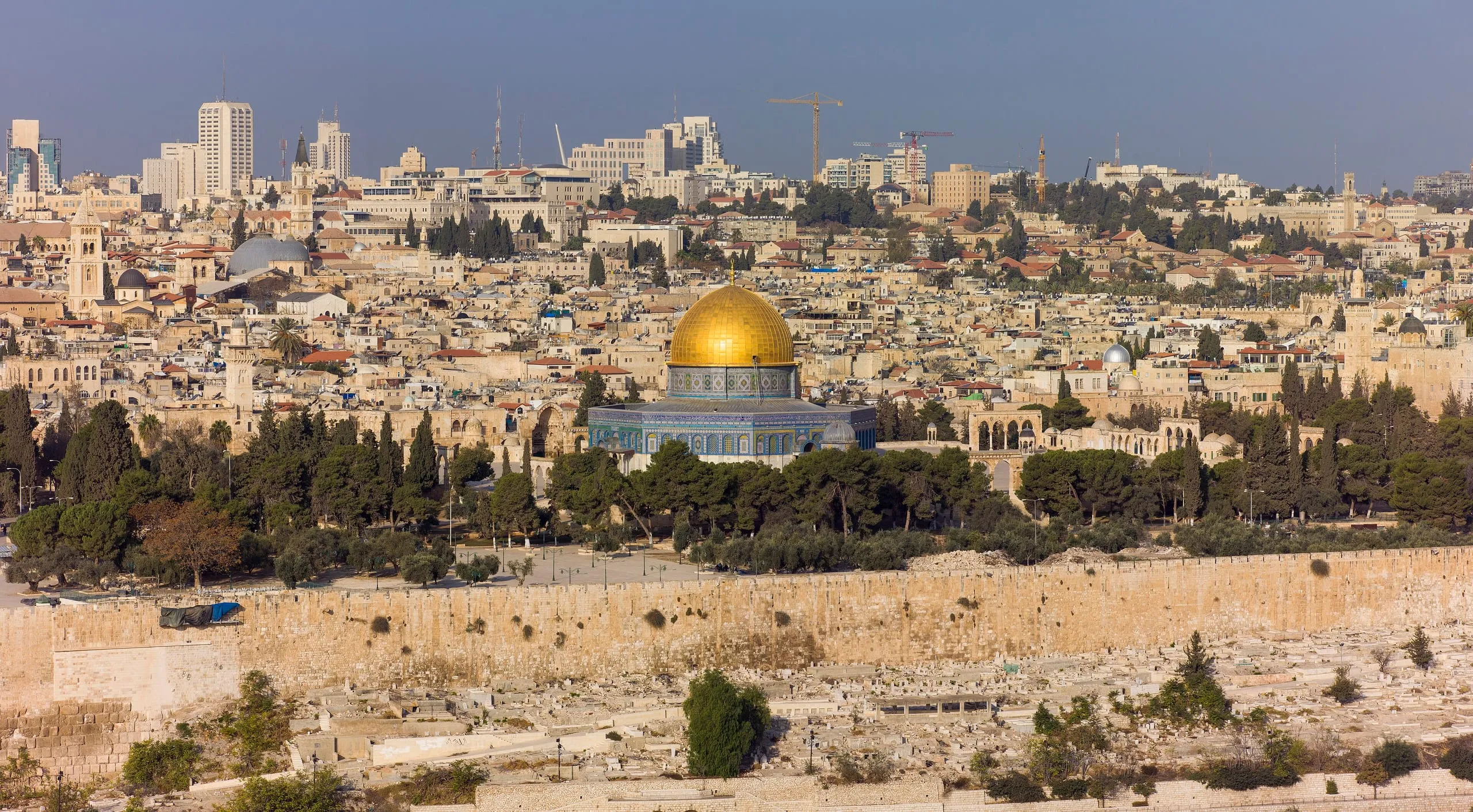 The Old City of Jerusalem seen from the Mount of Olives, with the gold Dome of the Rock at its centre and the limestone city rising behind it.